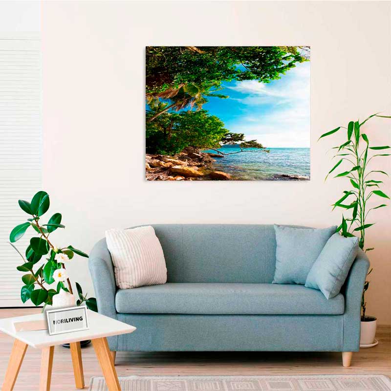 Ein gemütliches Wohnzimmer mit einem blauen Sofa und einem Bild, das eine tropische Landschaft mit Meer und Bäumen zeigt.