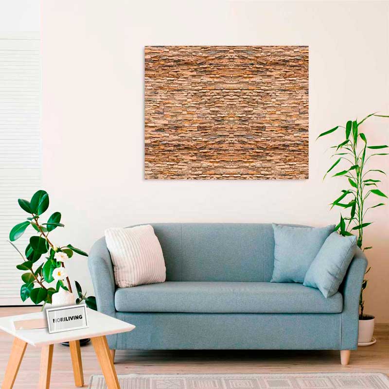 Ein stilvoll eingerichtetes Wohnzimmer mit einem blauen Sofa, einem Tisch mit Pflanze und einem großen Wandbild in Steinoptik.