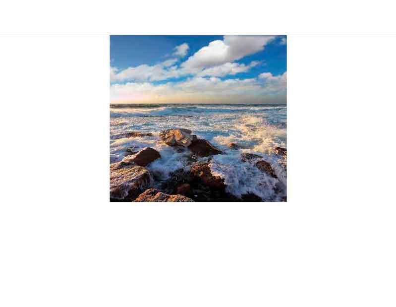 Felsen an der Küste mit brechenden Wellen unter einem bewölkten Himmel