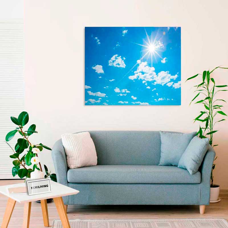 Helles Wohnzimmer mit blauem Sofa, weißem Tisch und einem Bild des blauen Himmels mit Sonne an der Wand