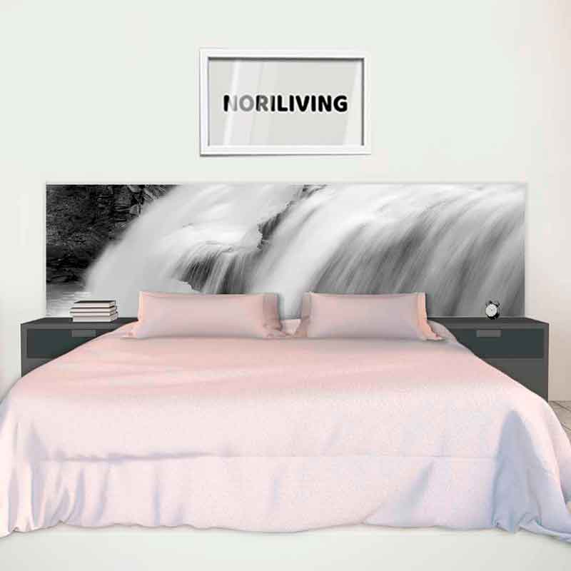 Ein stilvolles Schlafzimmer mit einem großen Bett, Nachtkästchen und einer Wasserfall-Bettrückwand. An der Wand hängt ein Bildrahmen mit der Aufschrift 'NORILIVING'.