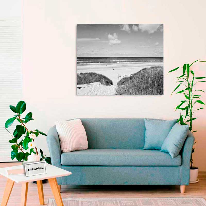 Ein modernes Wohnzimmer mit einem blauen Sofa und einem Schwarz-Weiß-Bild einer Strandlandschaft an der Wand