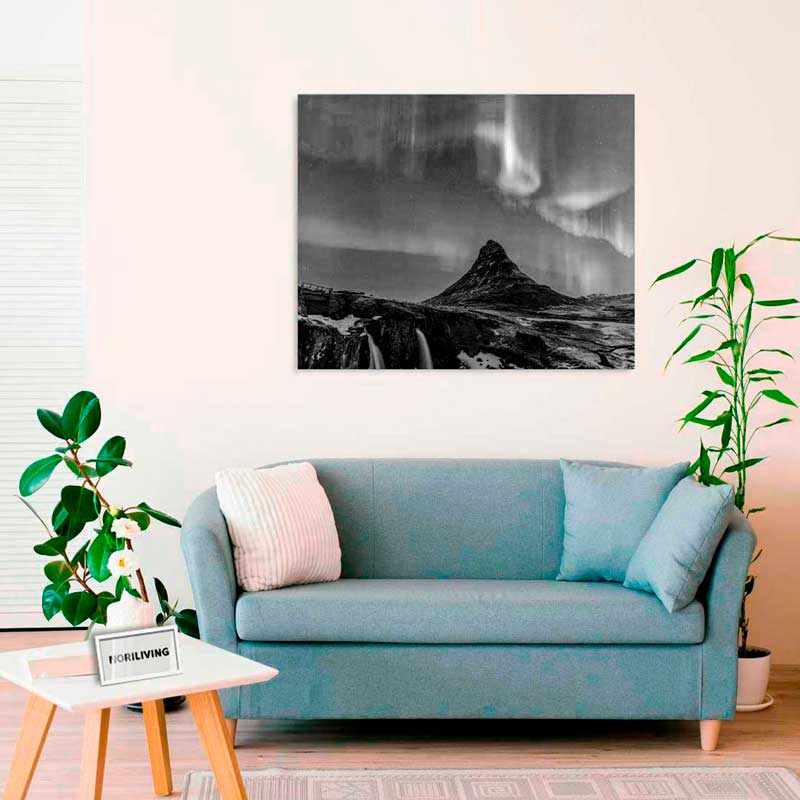 Farblich abgestimmtes Wohnzimmer mit einem Bild von Nordlichtern über einem Berg, aufgehängt über einem blauen Sofa