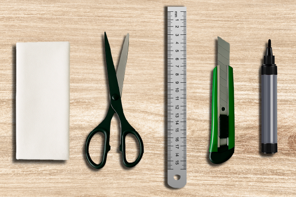 Ein Satz mit Büromaterialien bestehend aus Schere, Lineal, Cutter, Marker und Radiergummi auf einem Holzuntergrund