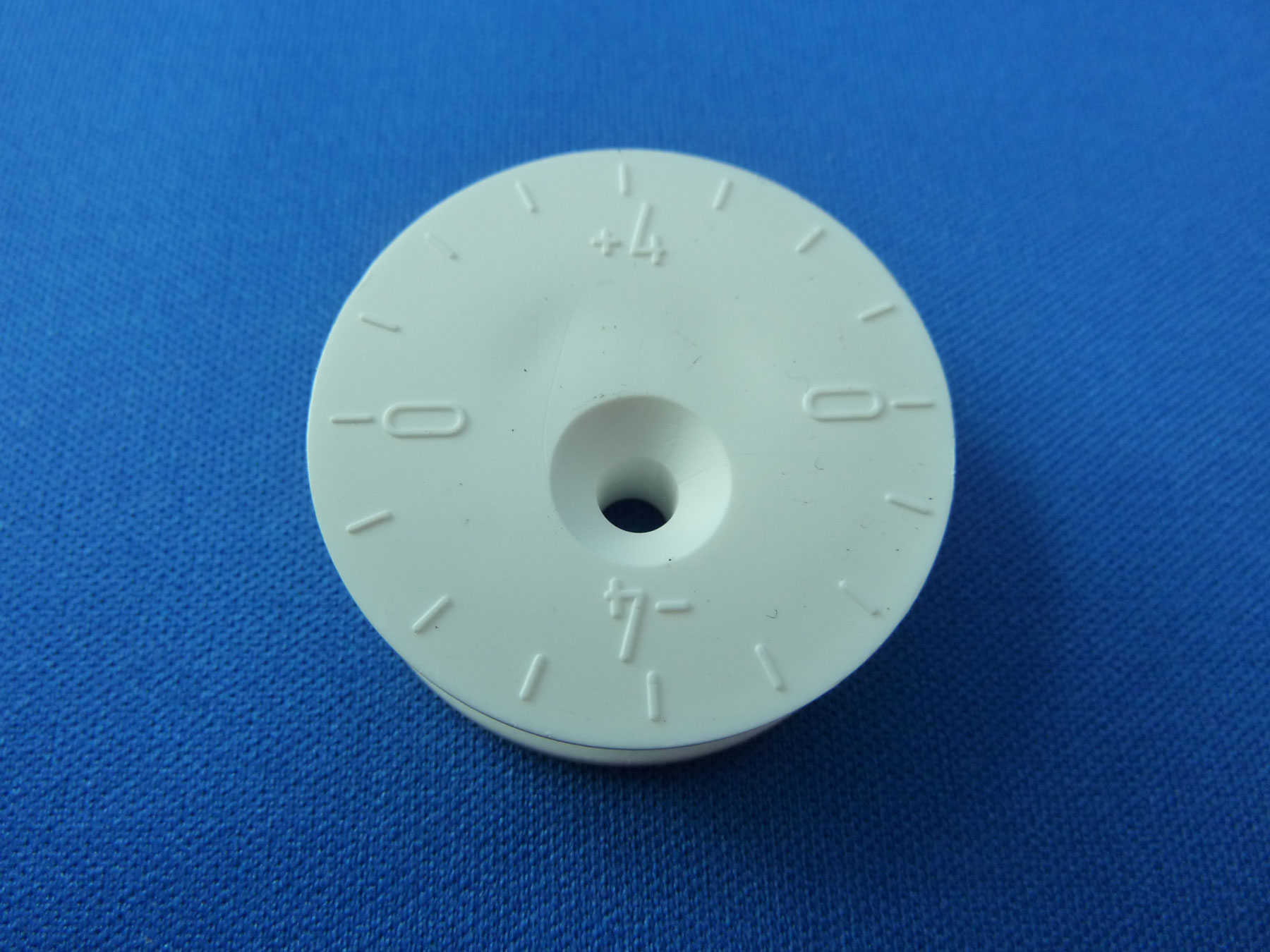 Nahaufnahme eines weißen, kreisförmigen Plastikmoduls mit Ziffern auf einer blauen Oberfläche